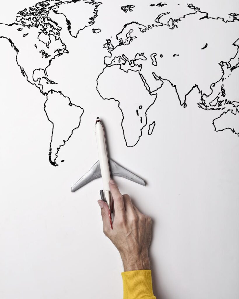 International Marketing & New Market Entry 3 Crop person in vibrant yellow clothes holding little gray plane against contour map on white wall as concept of tourism and adventure