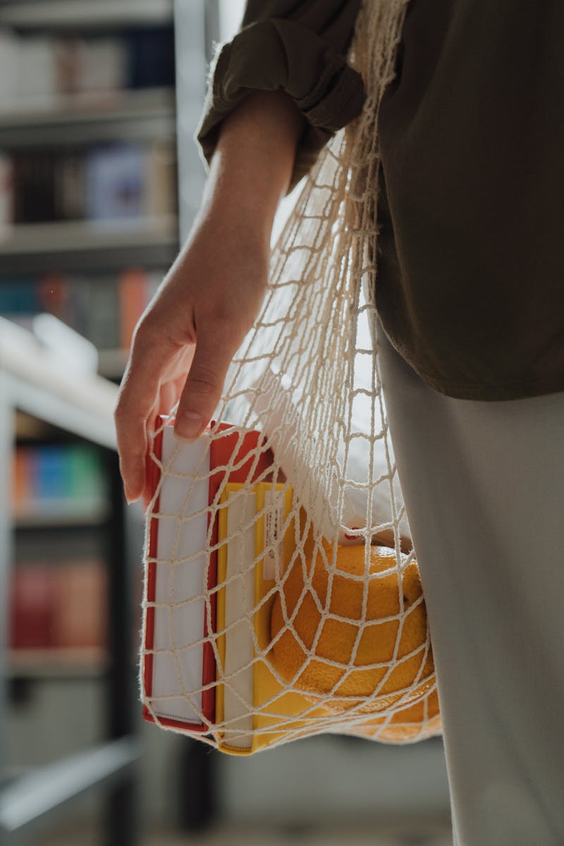 Social Media 6 Close-up of a woman holding a string bag with groceries and books, promoting zero waste lifestyle.
