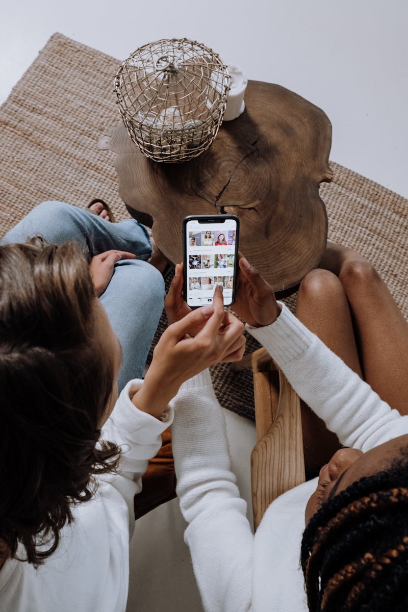 Diseño Web con WordPress para Marcas que Enamoran 1 Two people looking at social media on a smartphone at a wooden table.