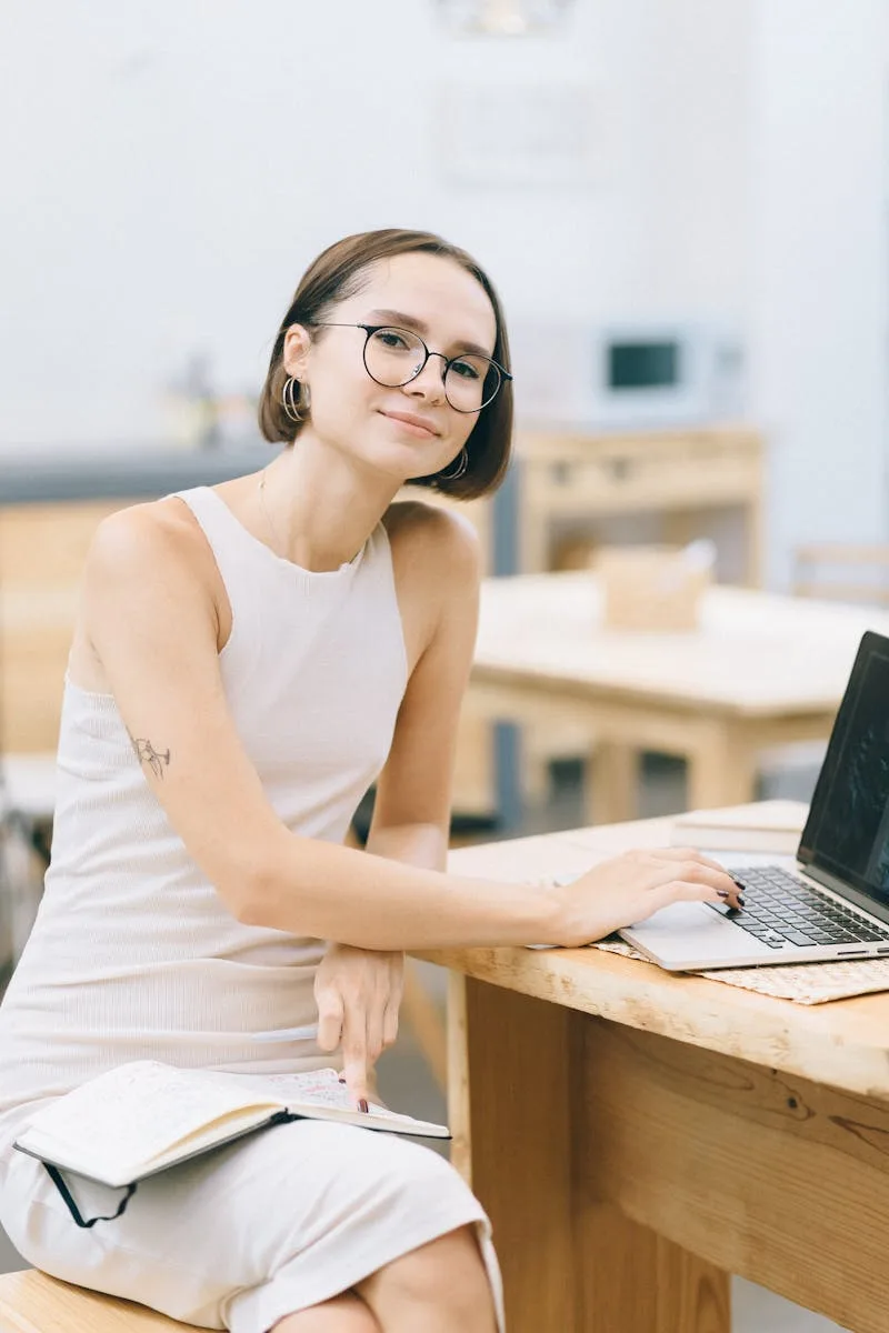Confident young woman working on a laptop in a cozy café, embodying remote work culture.