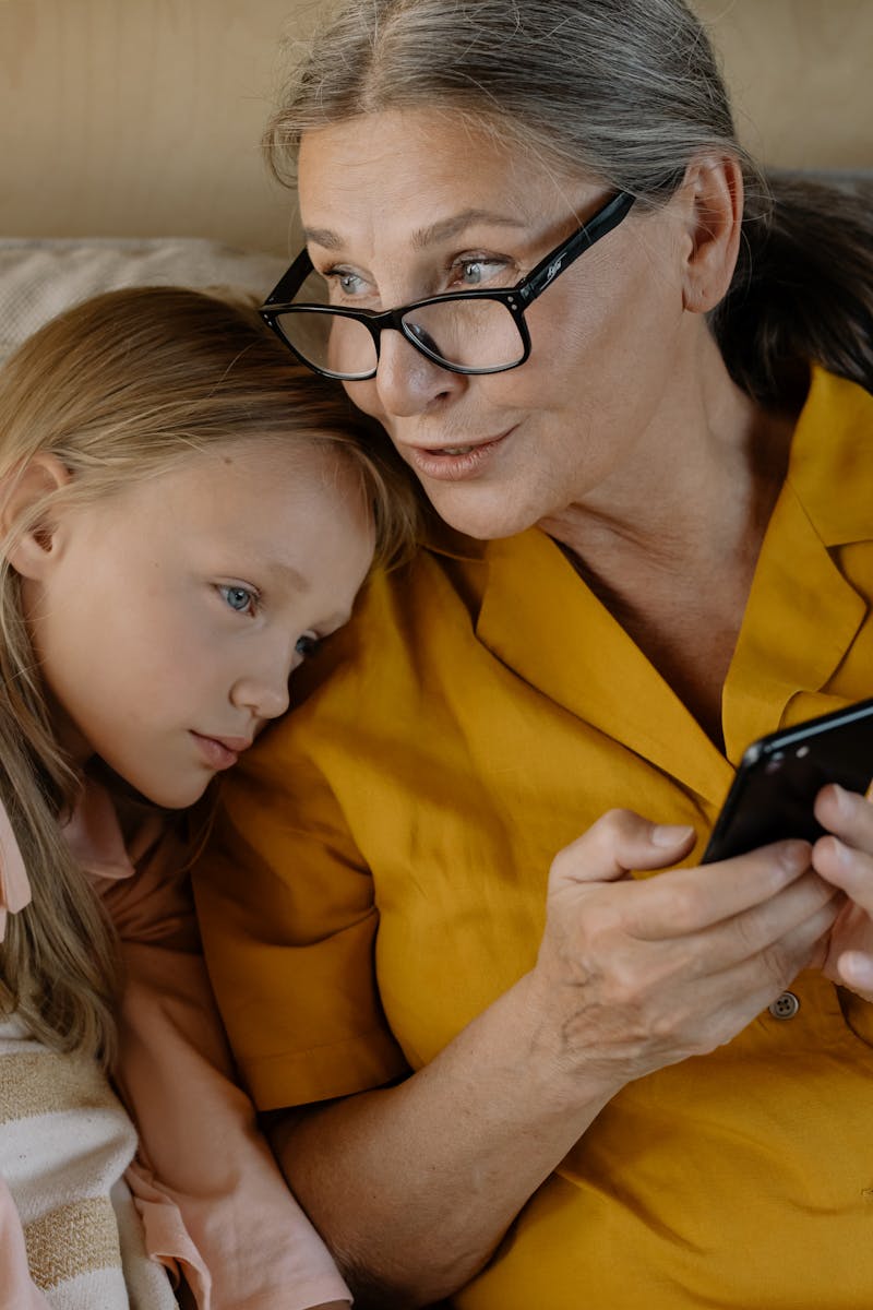 Diseño Web con WordPress para Marcas que Enamoran 2 Senior woman and young girl enjoying time together, bonding over a smartphone indoors.
