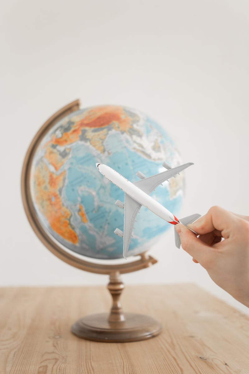 International Marketing & New Market Entry 2 Close-up of a hand with a toy airplane in front of a globe, symbolizing travel and exploration.