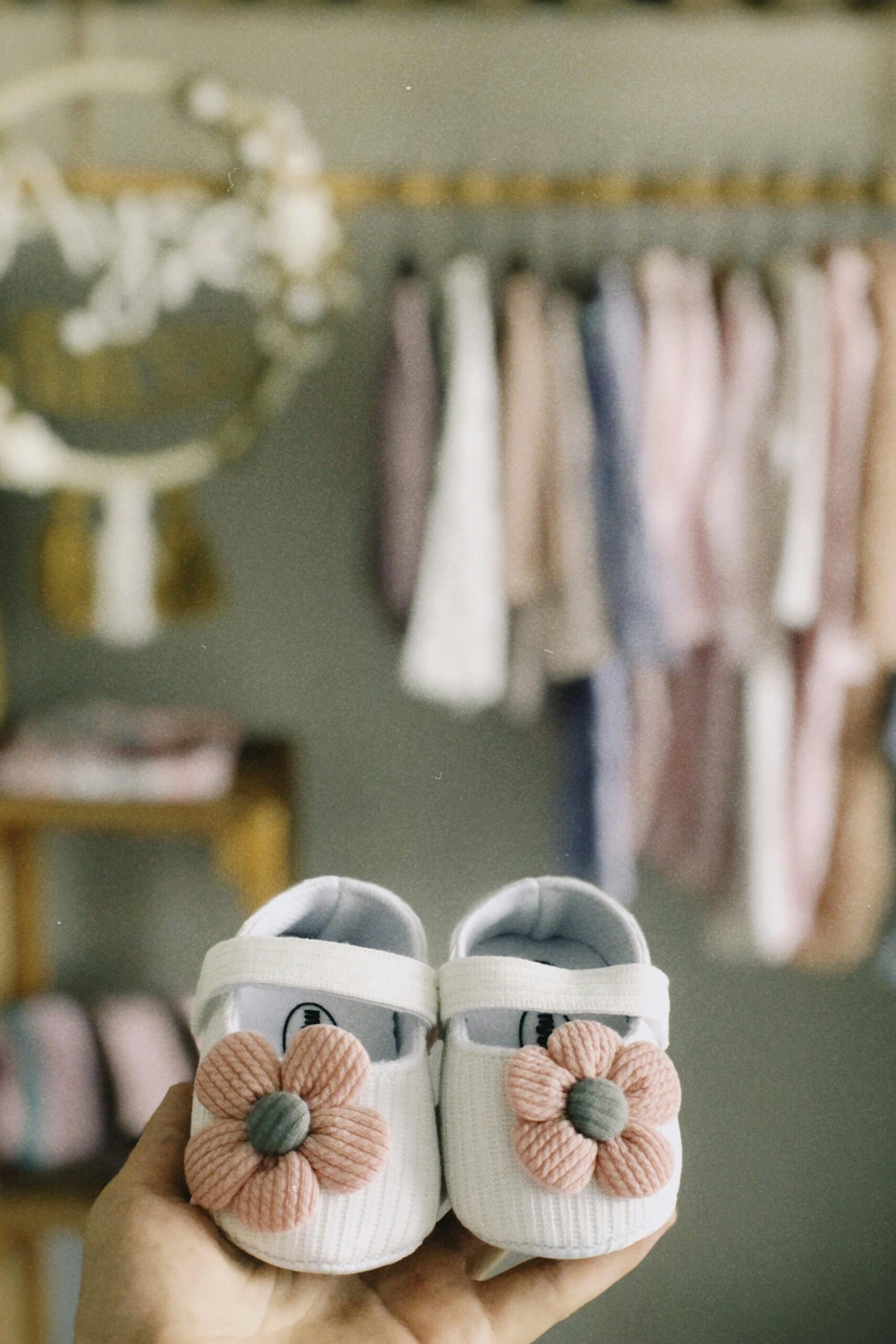 Brand Development for Baby Product Companies 1 Cute white baby shoes with pink floral decoration held in hand, perfect for newborn fashion.