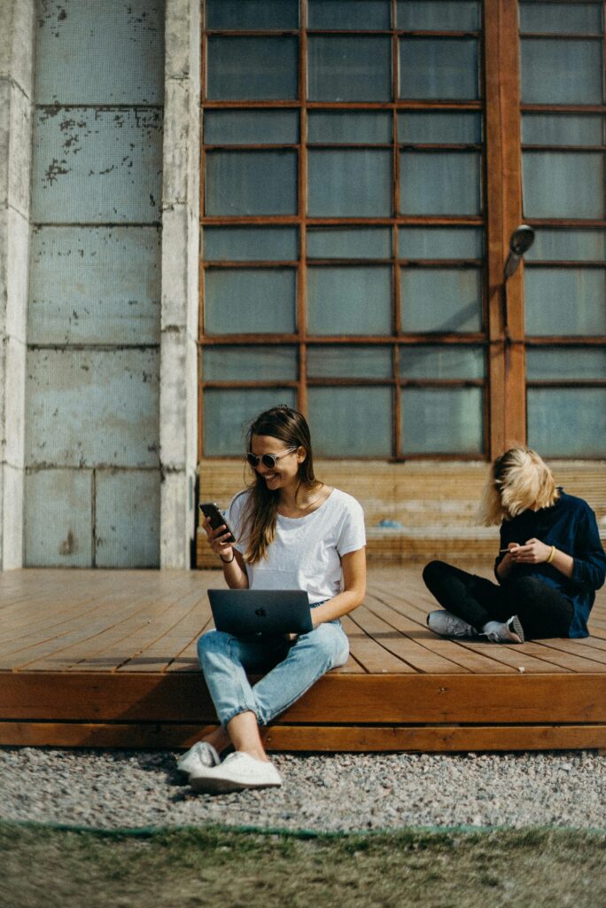 Social Media Marketing for Children's Brands 3 Two women working remotely on laptops outdoors, enjoying the sun. Perfect for freelance lifestyle themes.