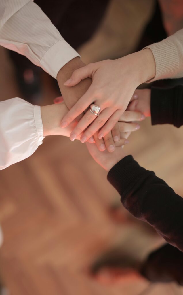 Brand Development for Baby Product Companies 4 Top view of faceless friends in different clothes stacking hands together while standing on wooden floor indoor on sunny day