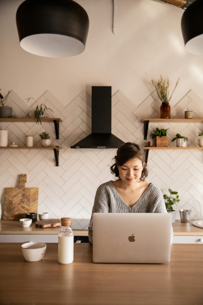 Amazon & Marketplace Marketing 3 Young female student in gray sweater sitting at wooden desk with laptop and bottle of milk near white bowl during distance education at home