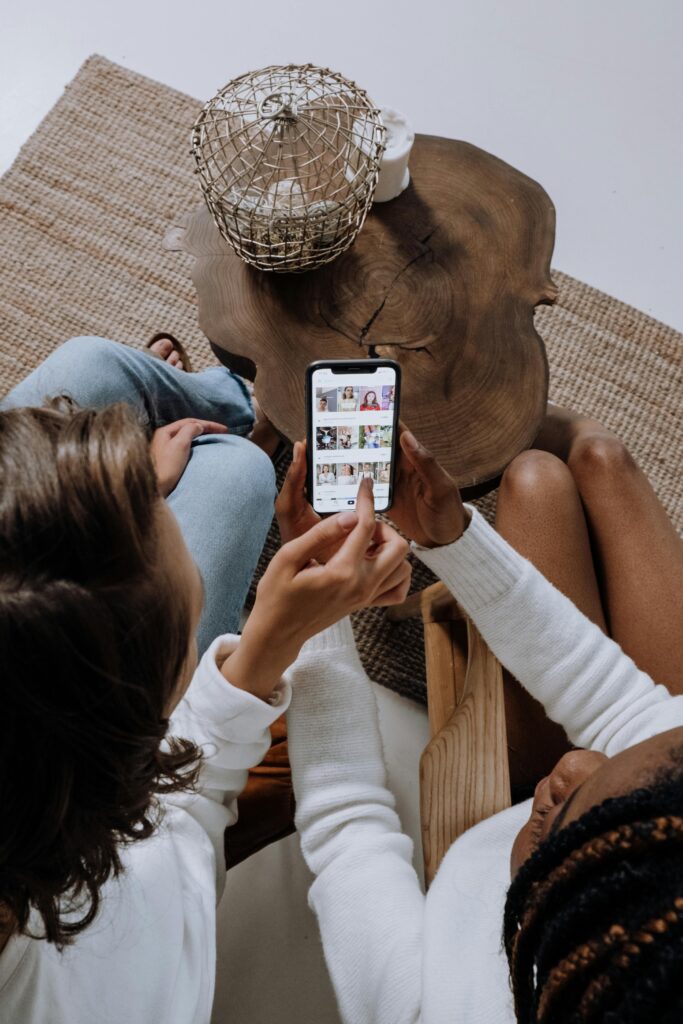 Espacios de Crianza y Centros Familiares 4 Two people looking at social media on a smartphone at a wooden table.