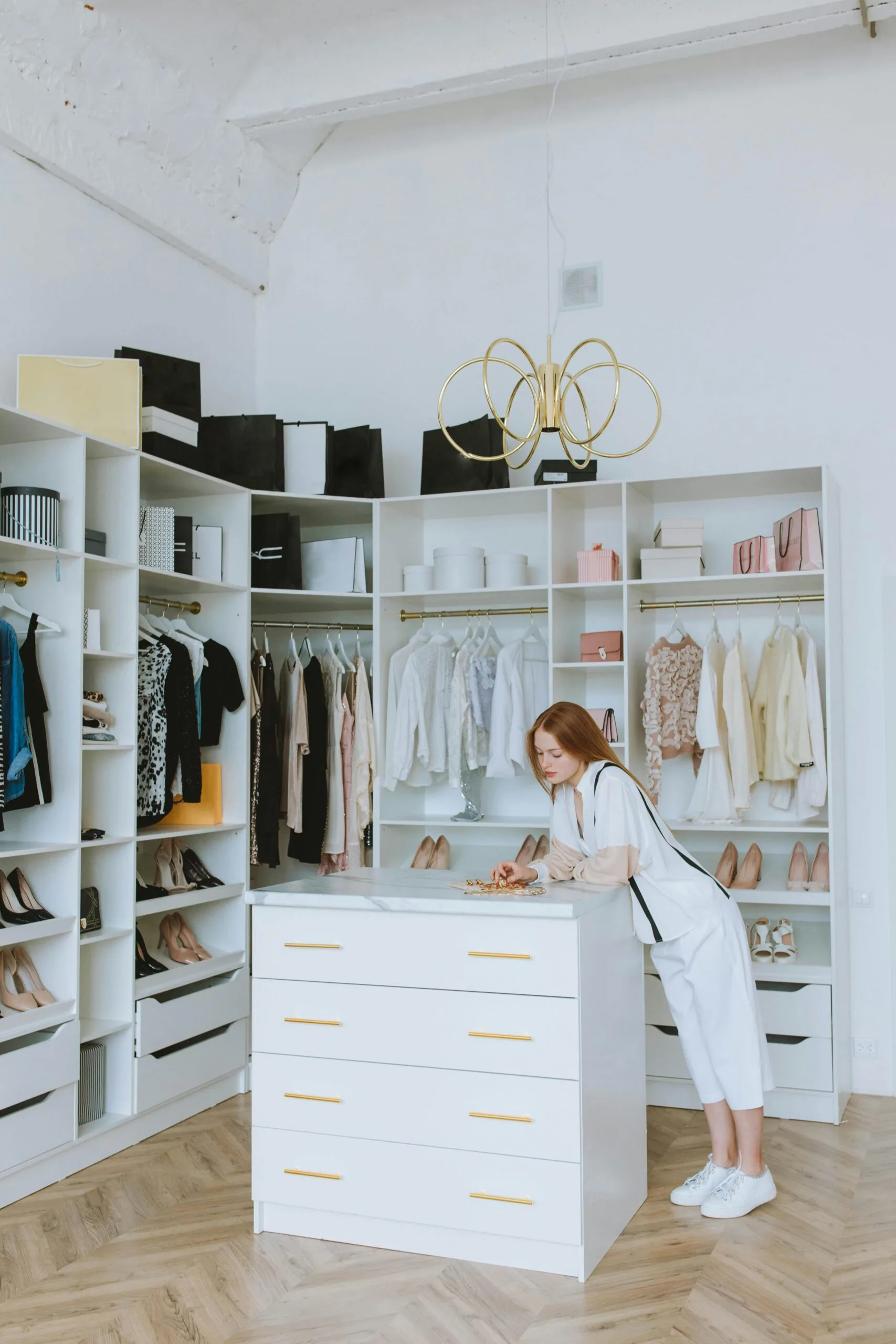 Elegant wardrobe with a red-haired woman organizing clothes in a modern fashion boutique.