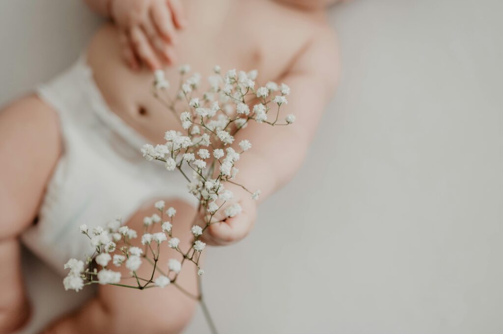 What Pages a Baby Brand Needs to Rank on Google 2 Portrait of a baby in a diaper delicately holding white flowers, emphasizing innocence.
