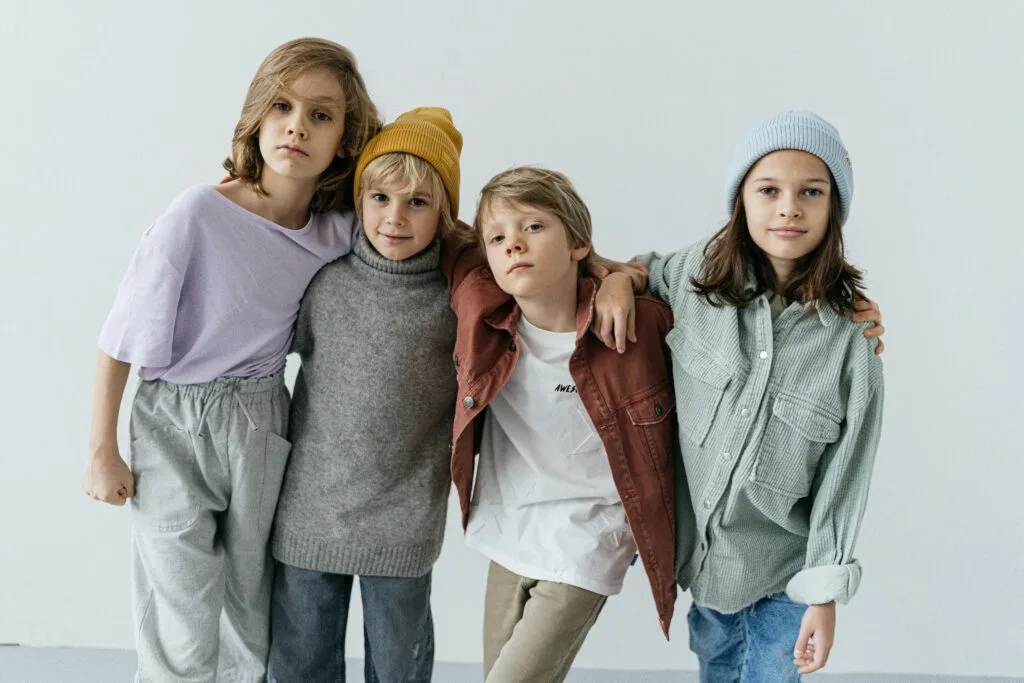 Group of fashionable kids posing in a studio setting wearing trendy outfits.
