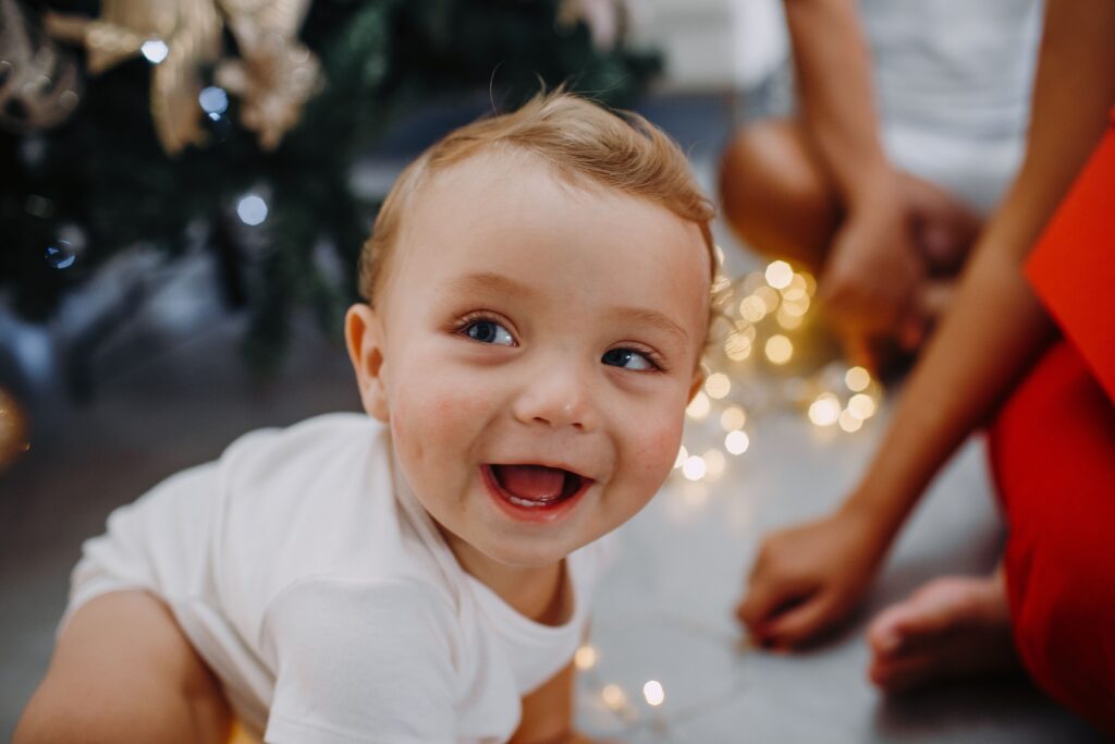 A happy baby enjoying Christmas lights and holiday atmosphere indoors.