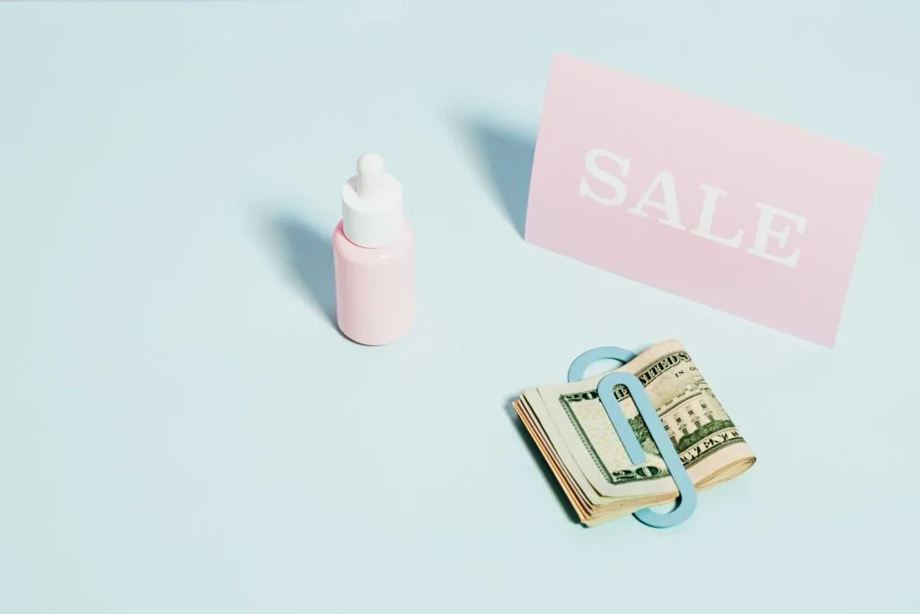 Aesthetic flat lay of a sale sign with US dollars and skincare product. Perfect for sales promotions.