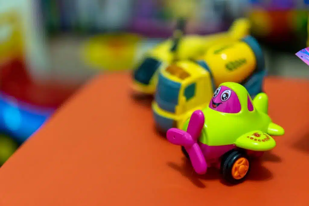 Publicidad de juguetes: campañas que conectan con familias 9 A vibrant toy airplane and concrete mixer on an orange table, creating a playful scene.