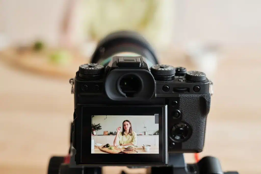 Macroinfluencers o microinfluencers en maternidad: cómo elegir 13 Caucasian woman vlogging at home with camera in a kitchen setting, captured indoors.