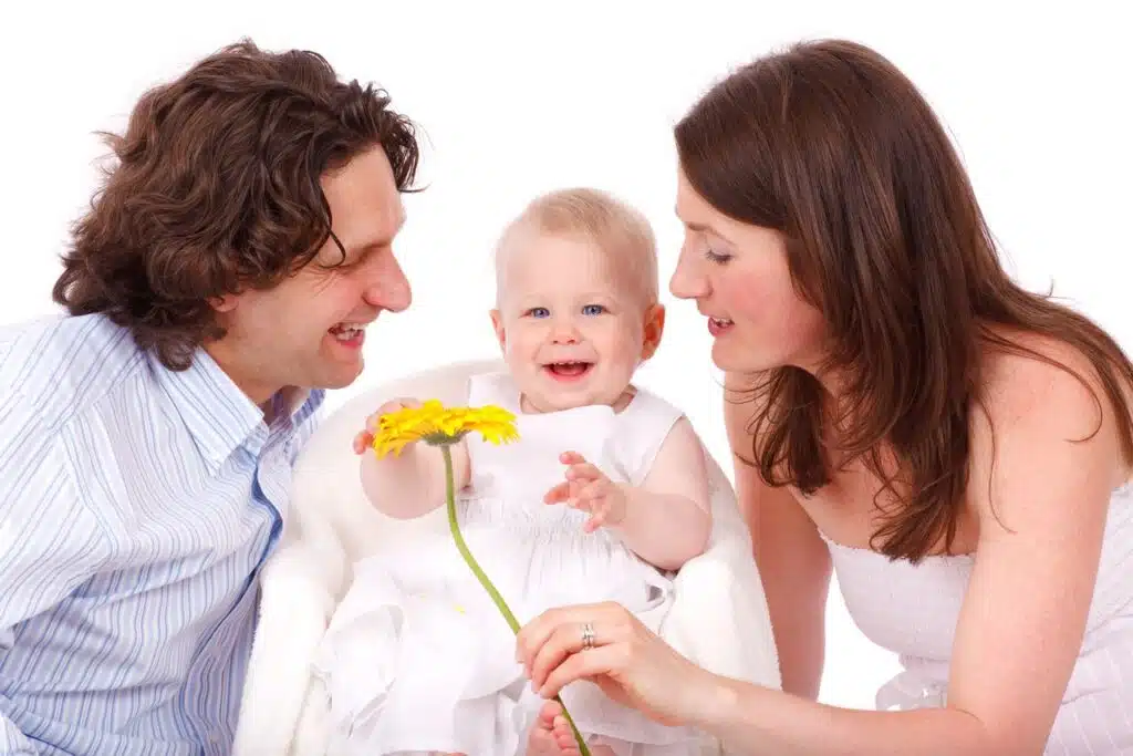 A joyful family moment with parents and baby holding a flower.