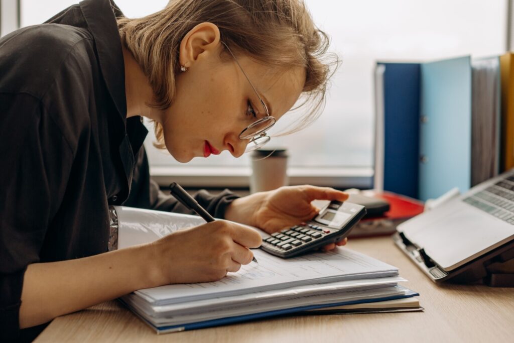 Digital Growth Audit for Baby Brands 2 Young woman diligently working on accounting with a calculator and documents. Perfect for business and finance themes.