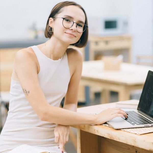 Mujer joven segura de sí misma trabajando en un portátil en un acogedor café, encarnando la cultura del trabajo remoto.