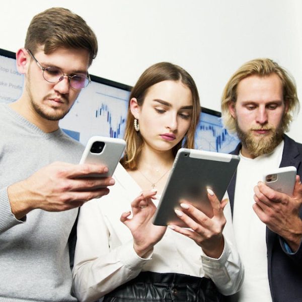 Young professionals engaged with digital devices, discussing business strategies indoors.