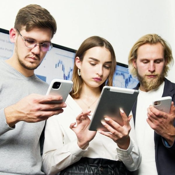 Jóvenes profesionales interactuando con dispositivos digitales, discutiendo estrategias de negocio en interiores.