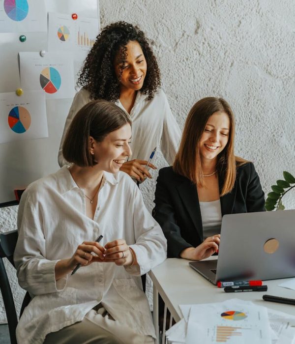 Tres empresarias colaboran con gráficos y un portátil en un entorno de oficina moderno.