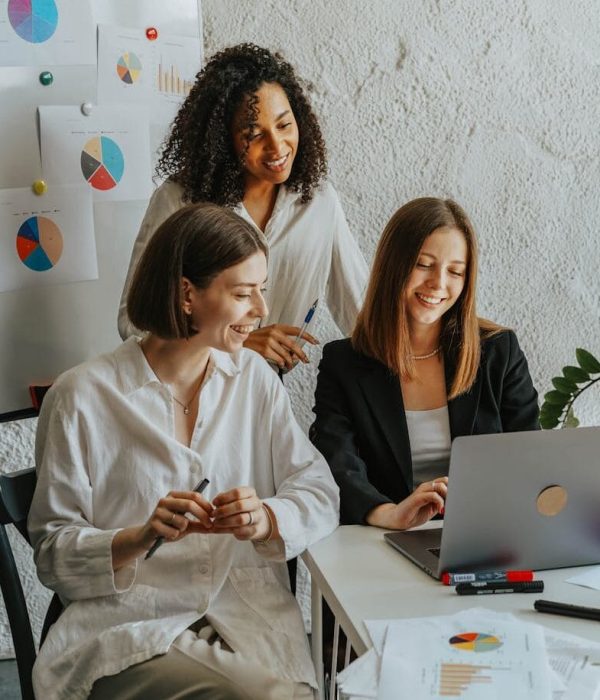 Tres empresarias colaboran con gráficos y un portátil en un entorno de oficina moderno.