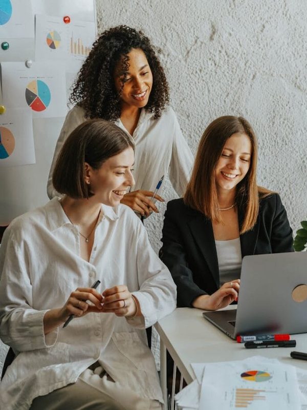 Tres empresarias colaboran con gráficos y un portátil en un entorno de oficina moderno.