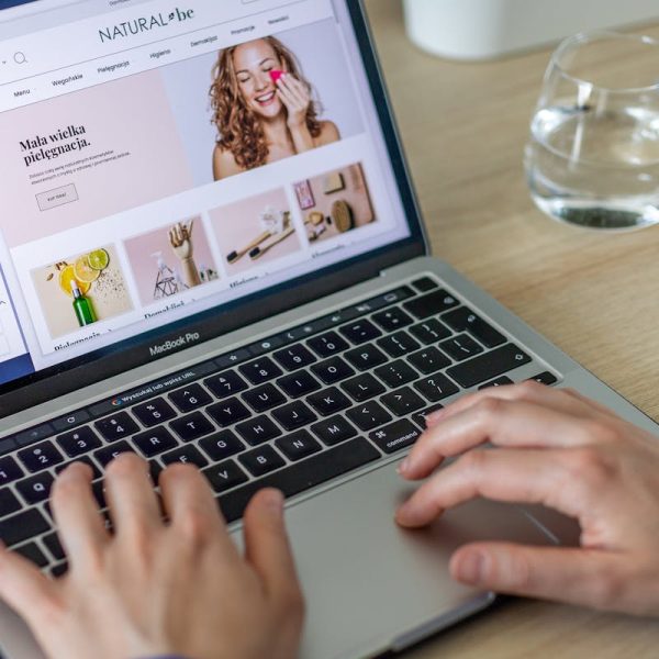 Hands typing on a laptop showing an e-commerce website in a modern office setting.