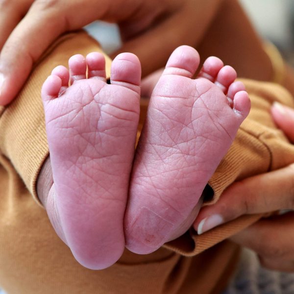 Tender close-up of a baby's feet cradled in a parent's hands, expressing love and care.