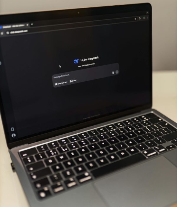 Close-up of a laptop showing an AI chat interface in a dimly lit room.