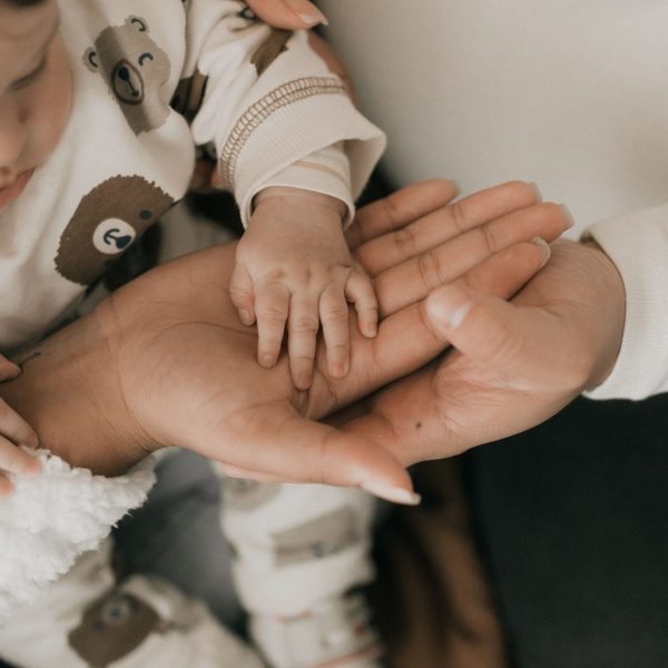 Close-up of a mother holding her baby's hand, symbolizing love and care.