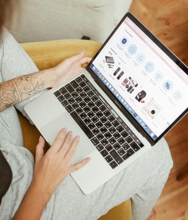 Woman with tattoos browsing online shopping site on a laptop indoors