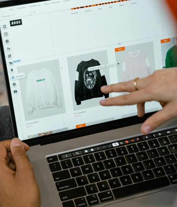 Close-up of hands interacting with a shopping website on a laptop screen indoors.