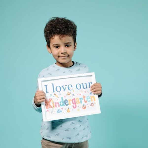 Child holding a sign about loving kindergarten in a studio setting.