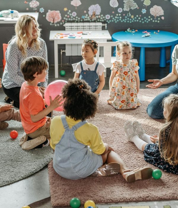 Children in circle time with teachers, engaging in a kindergarten classroom activity.